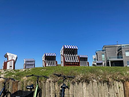 Strandkörbe stehen auf einer grünen Wiese vor blauen Himmel