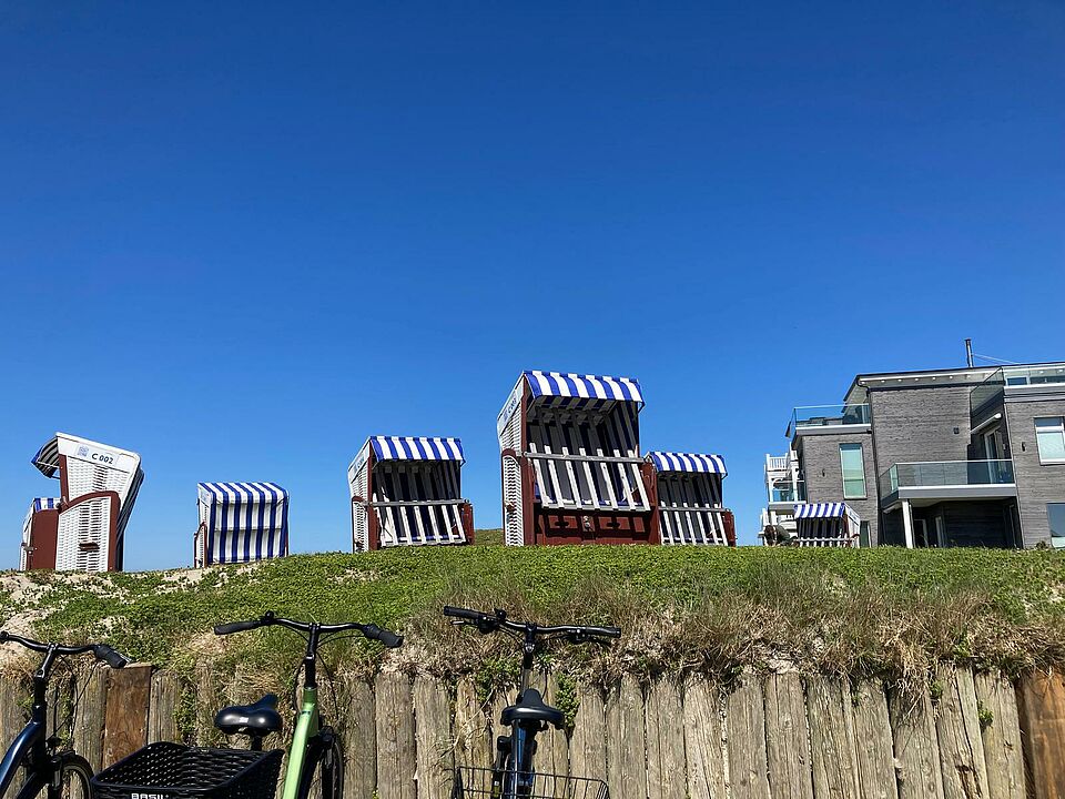 Strandkörbe stehen auf einer grünen Wiese vor blauen Himmel